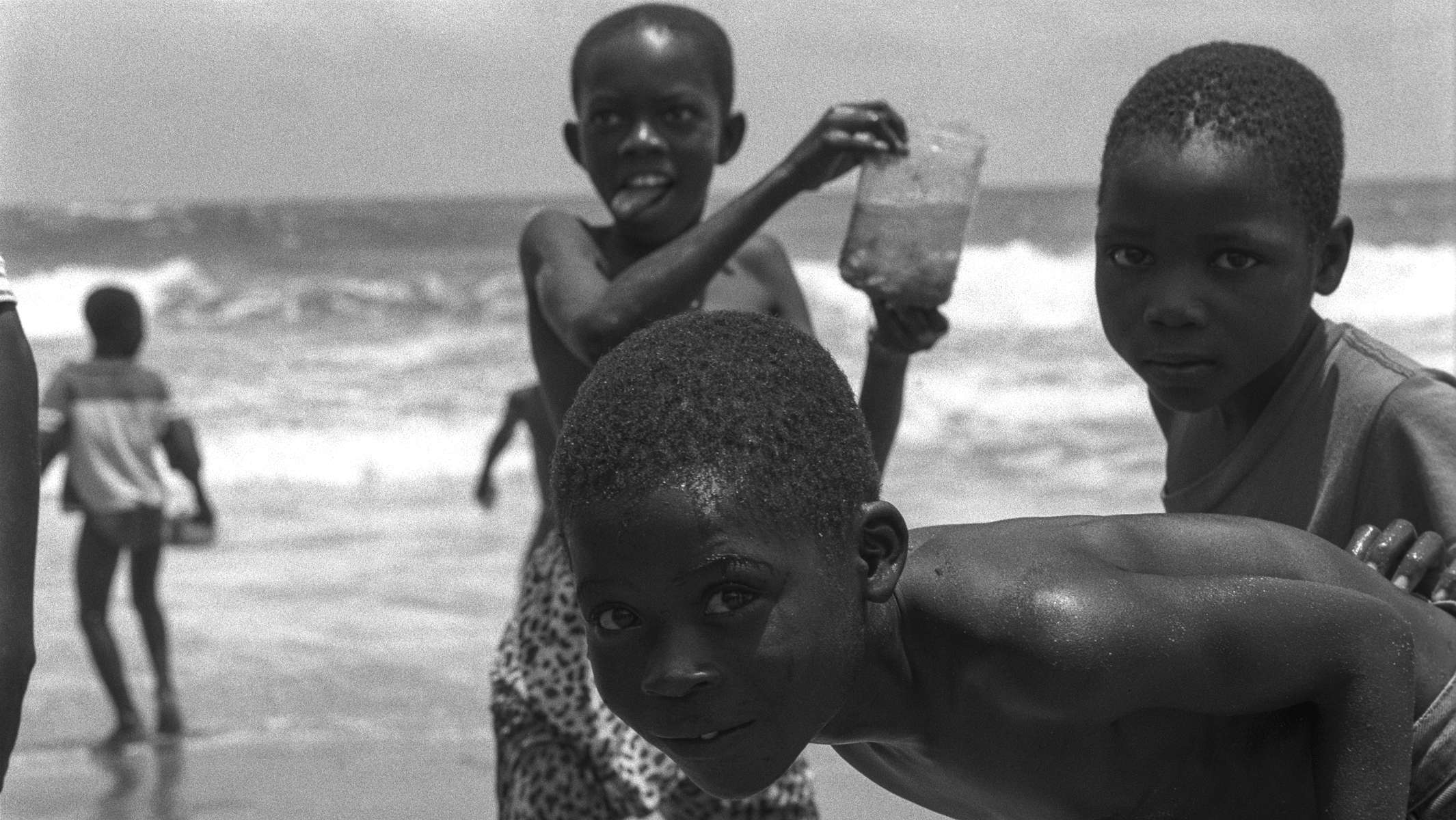 Afrikanische Kinder spielen am Strand mit Wasser, Foto in schwarzweiss. © Martin Geier