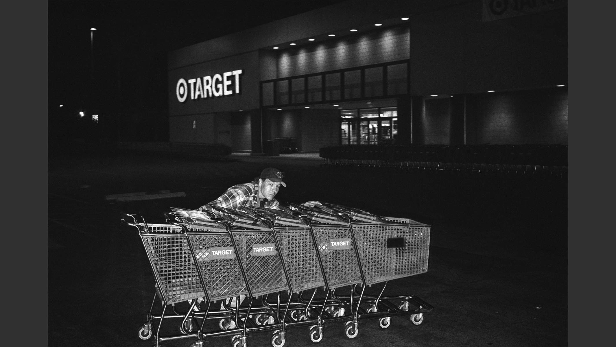 Mann schiebt Einkaufswagen nachts vor Supermarkt zusammen, Los Angeles, Foto in schwarzweiss. © Martin Geier
